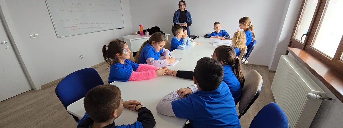 Sala de studiu — copii lucrând la teme alături de profesor
